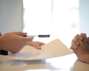 Hands holding paperwork across a negotiation table