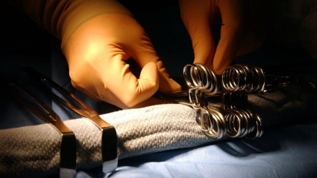 Close-up of surgical tools and gloved hands during a medical operation.