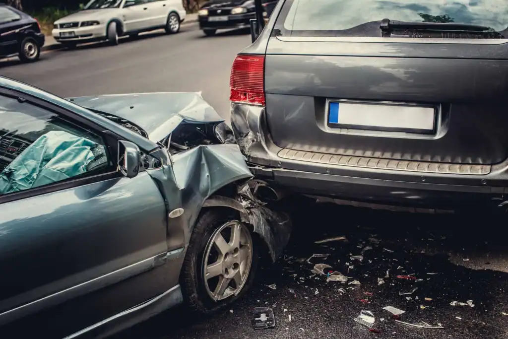 Car crash damage to front of gray sedan and rear of black SUV.