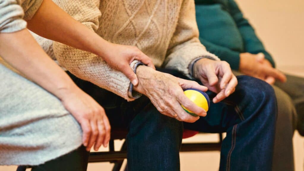Elderly woman participating in physical therapy with a yellow ball for mobility.