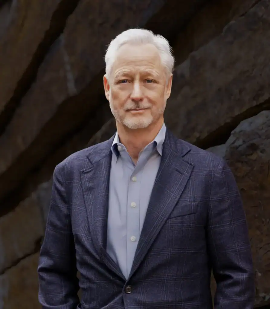 Senior male lawyer in a professional suit standing outdoors near rocks.