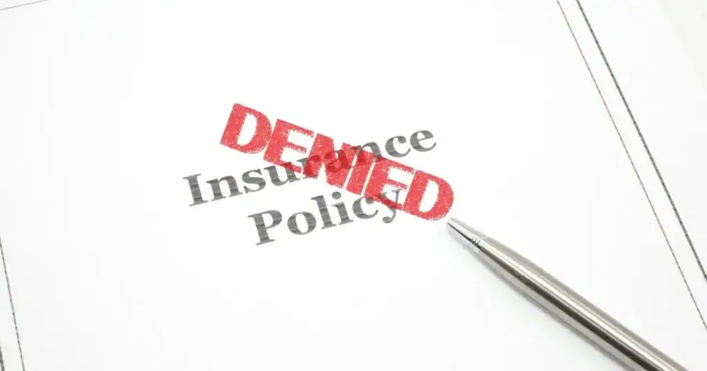 Insurance claim denied document with red stamped 'DENIED' and pen.