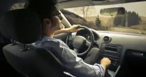 Young man driving a car on a scenic Oklahoma highway.